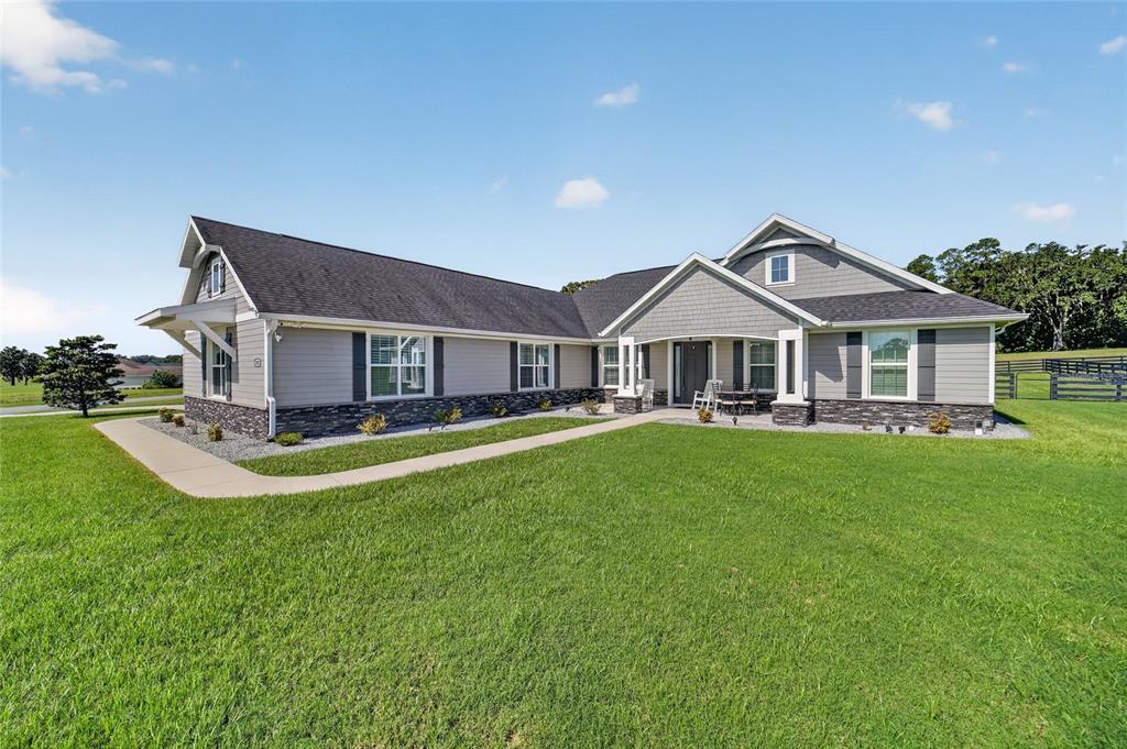 A single-story house with gray siding, stone veneer, and a dark shingled roof — 1971 NW 86TH PLACE, OCALA, FL