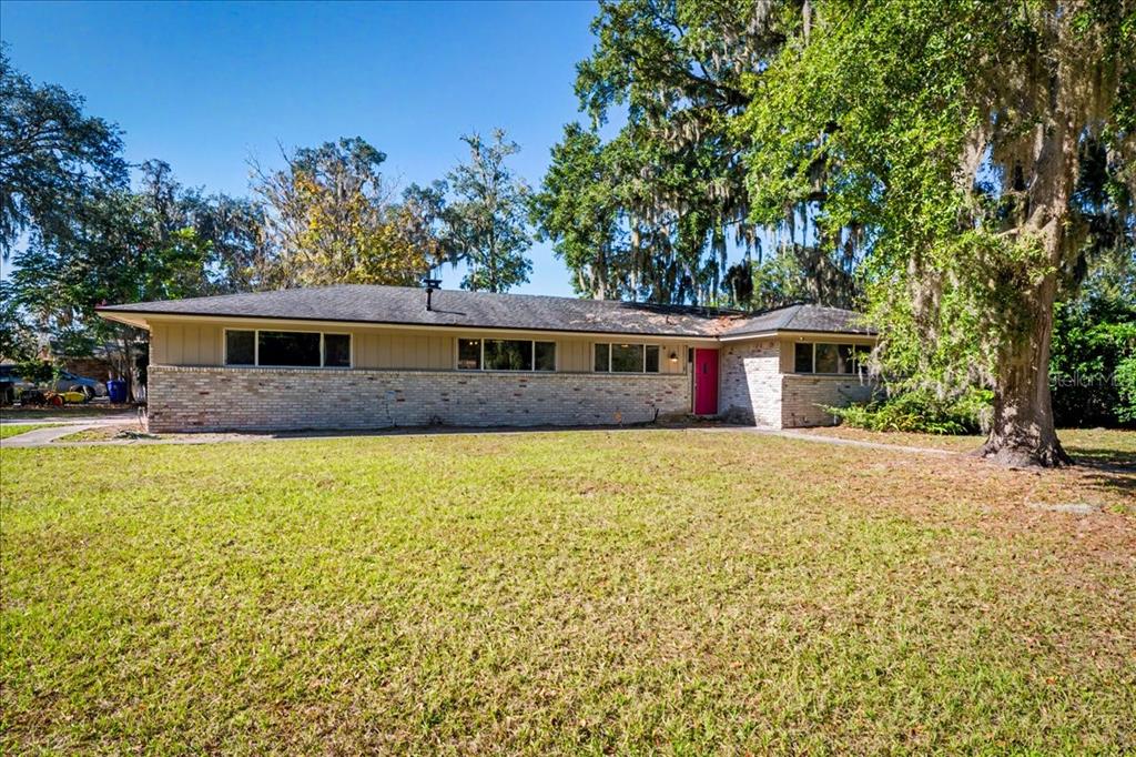 A single-story ranch house with a brick facade, beige siding, and a bright pink front door — 2349 MOODY AVENUE, ORANGE PARK, FL