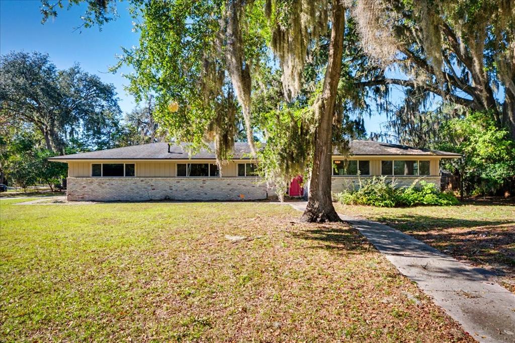 A single-story ranch-style house with a brick base and a concrete walkway under large trees — 2349 MOODY AVENUE, ORANGE PARK, FL