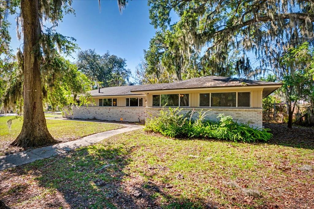 A single-story house with a brick facade and large windows sits under moss-draped oak trees — 2349 MOODY AVENUE, ORANGE PARK, FL