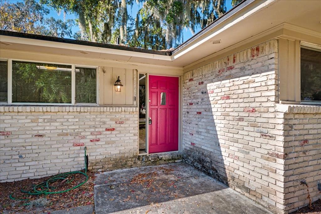 A house exterior features a bright pink front door, white brick walls, and a concrete porch — 2349 MOODY AVENUE, ORANGE PARK, FL