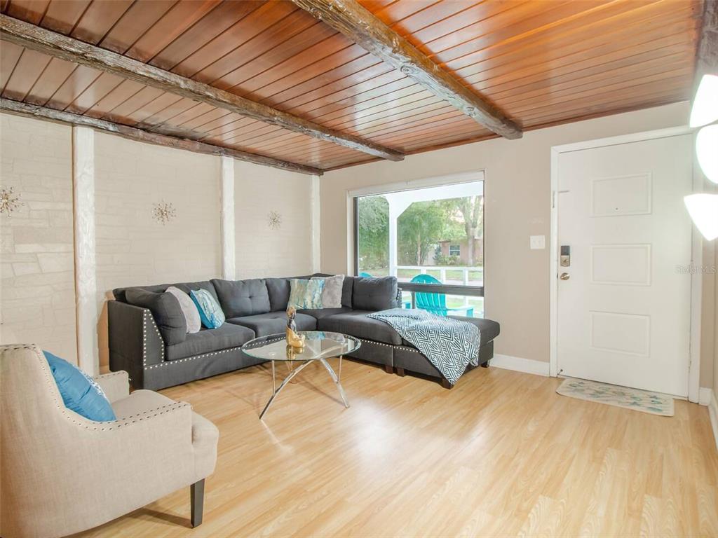 A living room features a wood-paneled ceiling, light wood flooring, and a gray sectional sofa — 1245 CATALPA LANE, ORLANDO, FL