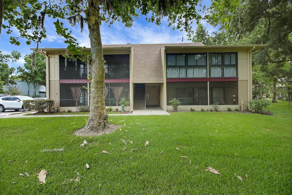 A two-story apartment building features screened-in porches, tan siding, and a central staircase — 220 MOREE LOOP UNIT 2, WINTER SPRINGS, FL