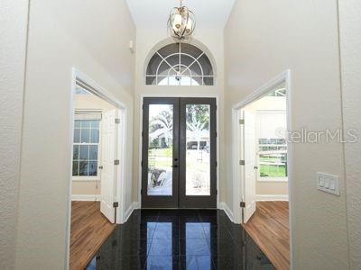 A foyer with black tile flooring leads to a double-door entrance with an arched window — 16 OAKLAND POINTE CIRCLE, OAKLAND, FL