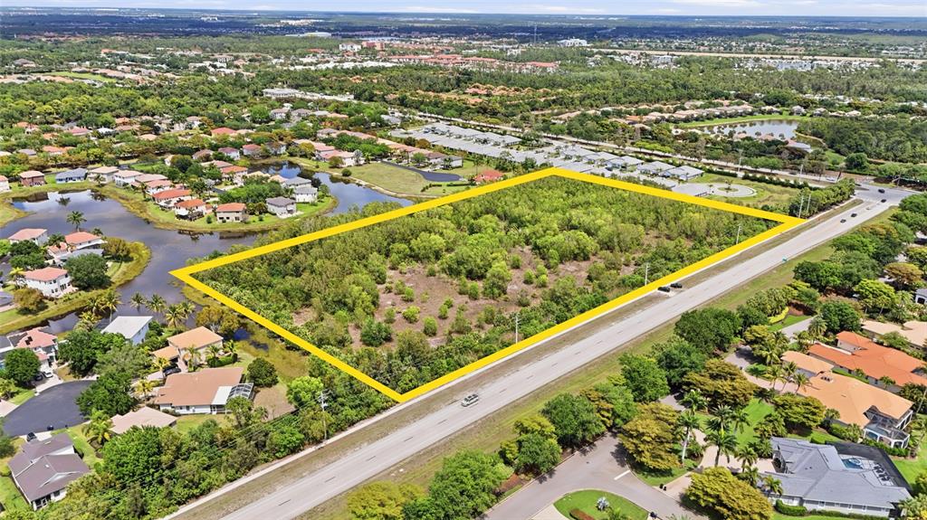 An aerial view shows a rectangular, tree-covered vacant lot outlined in yellow next to a road — WILLIAMS ROAD, ESTERO, FL