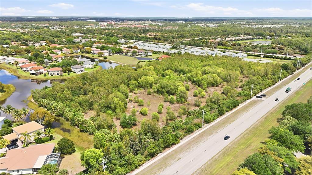 An aerial view shows a vacant, wooded lot situated between a residential neighborhood and road — WILLIAMS ROAD, ESTERO, FL
