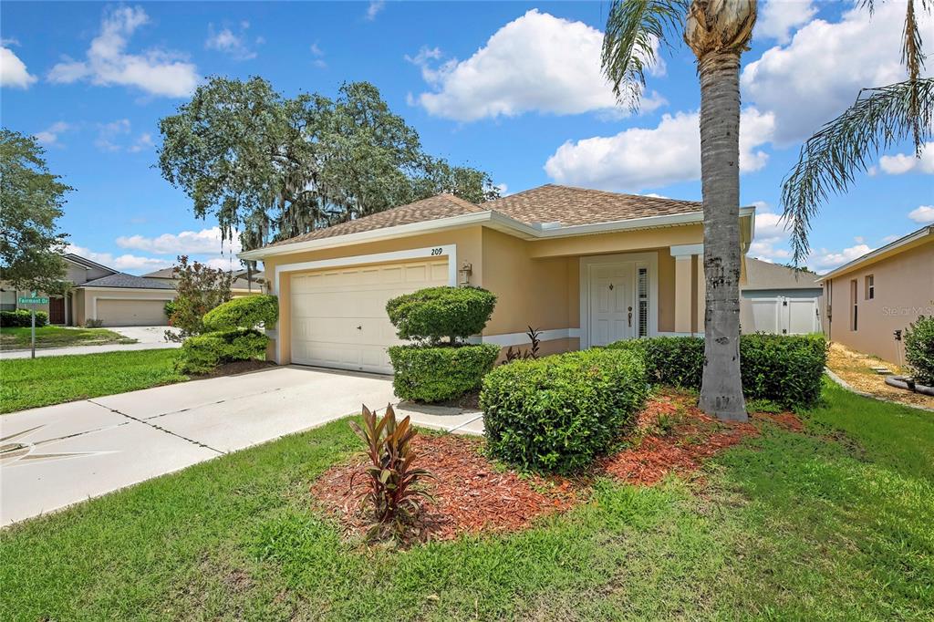 A single-story house with a beige exterior, a two-car garage, and a manicured front lawn — 209 WINTHROP DRIVE, SPRING HILL, FL
