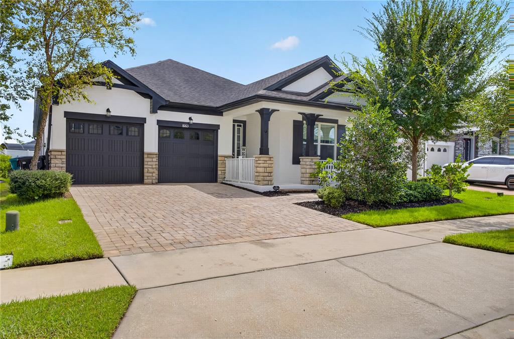 A single-story house with a two-car garage, stone accents, and a paved driveway — 8163 CORKFIELD AVENUE, ORLANDO, FL