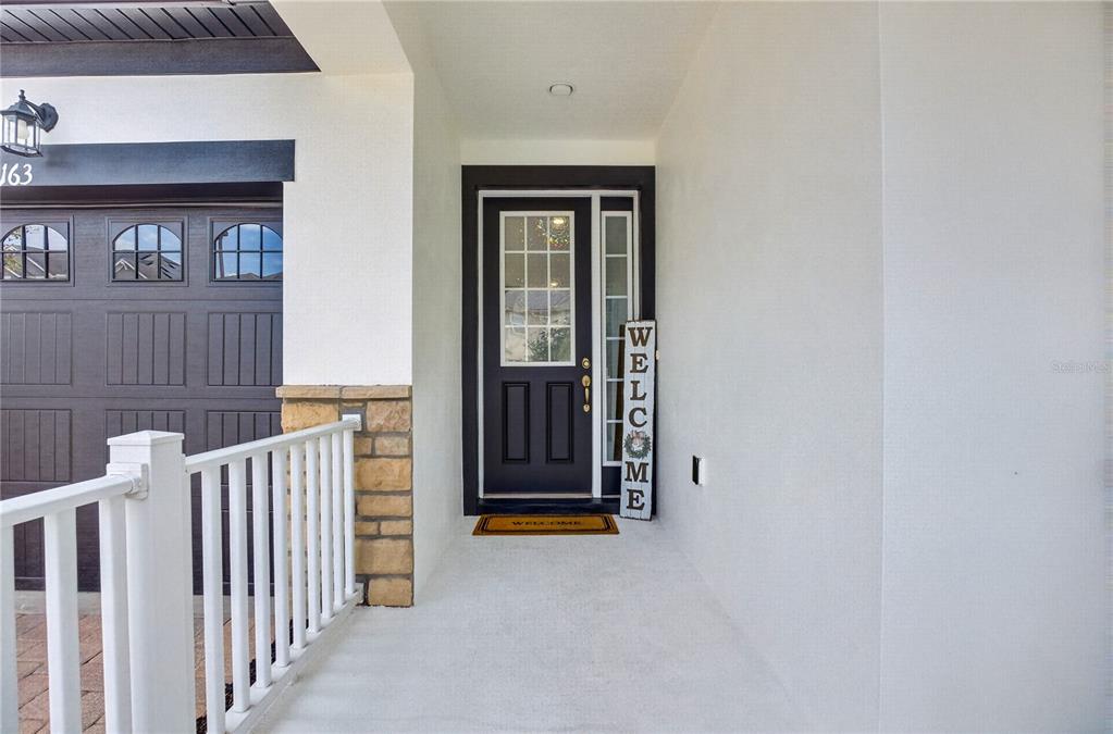 A covered entryway features a dark front door with a side window and stone accents — 8163 CORKFIELD AVENUE, ORLANDO, FL