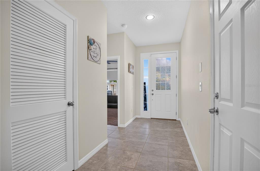 A tiled entryway features a white front door with glass panels and a louvered closet door — 8163 CORKFIELD AVENUE, ORLANDO, FL