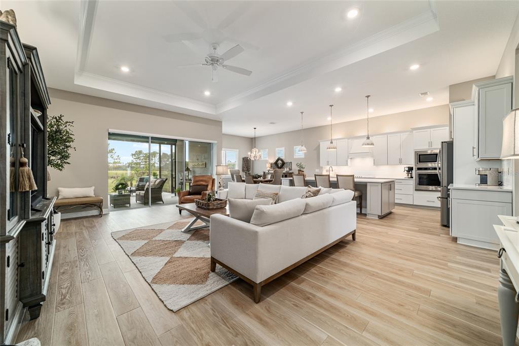 An open-concept living room and kitchen with white cabinetry, light wood flooring, and sliding doors — 8606 SW 61ST LOOP, OCALA, FL