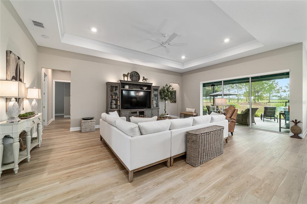A living room features a white sectional sofa, tray ceiling, and sliding glass doors to a patio — 8606 SW 61ST LOOP, OCALA, FL