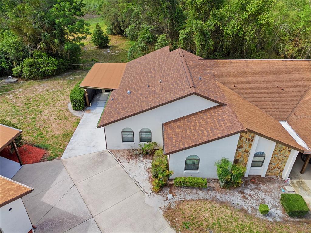 An aerial view of a house with a brown shingled roof and a concrete driveway — 9199 LINGROVE ROAD, WEEKI WACHEE, FL