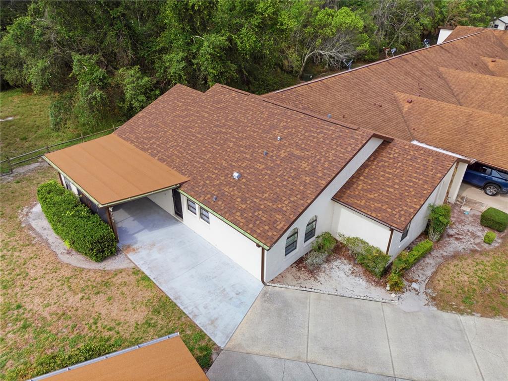 An aerial view shows a single-story house with a brown shingled roof and carport — 9199 LINGROVE ROAD, WEEKI WACHEE, FL