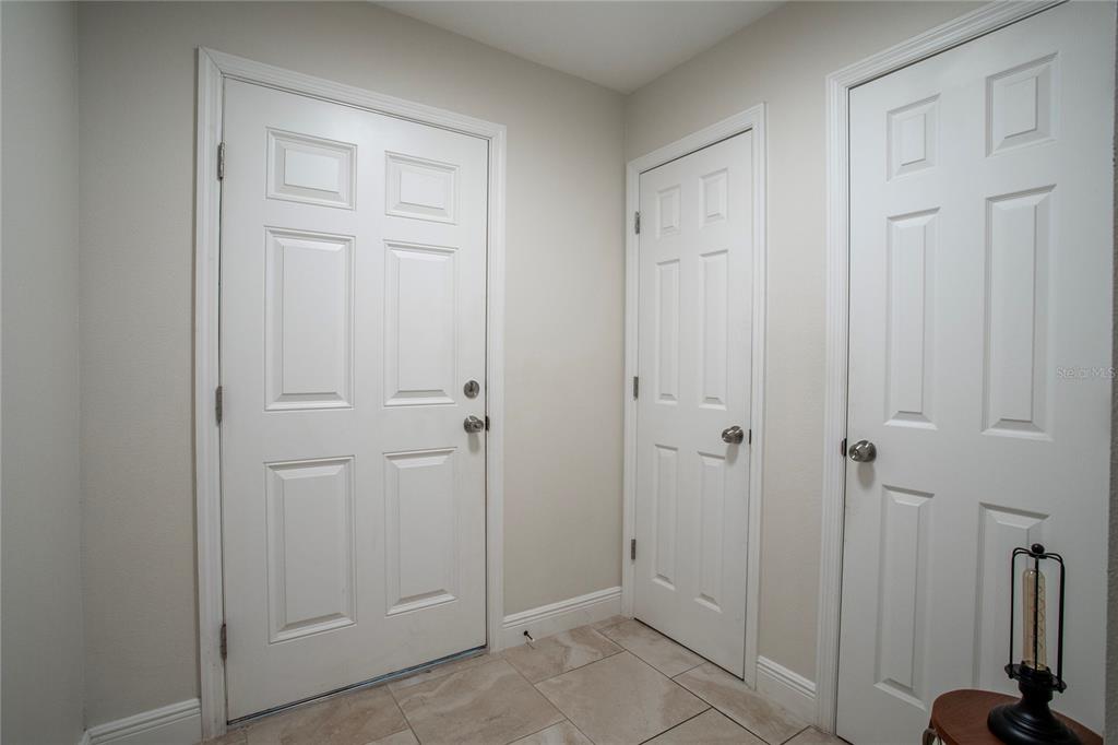 An entryway features three white six-panel doors and light-colored tile flooring — 1202 S DEWEY STREET, EUSTIS, FL