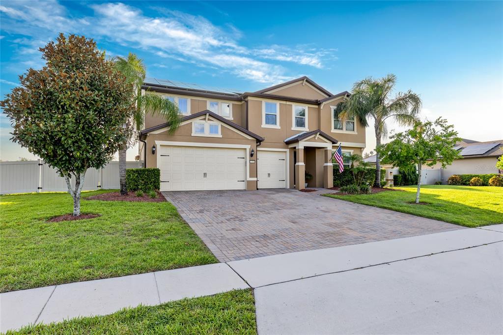 A two-story suburban house with a paved driveway, solar panels, and palm trees at dusk — 3344 KAYAK WAY, ORLANDO, FL
