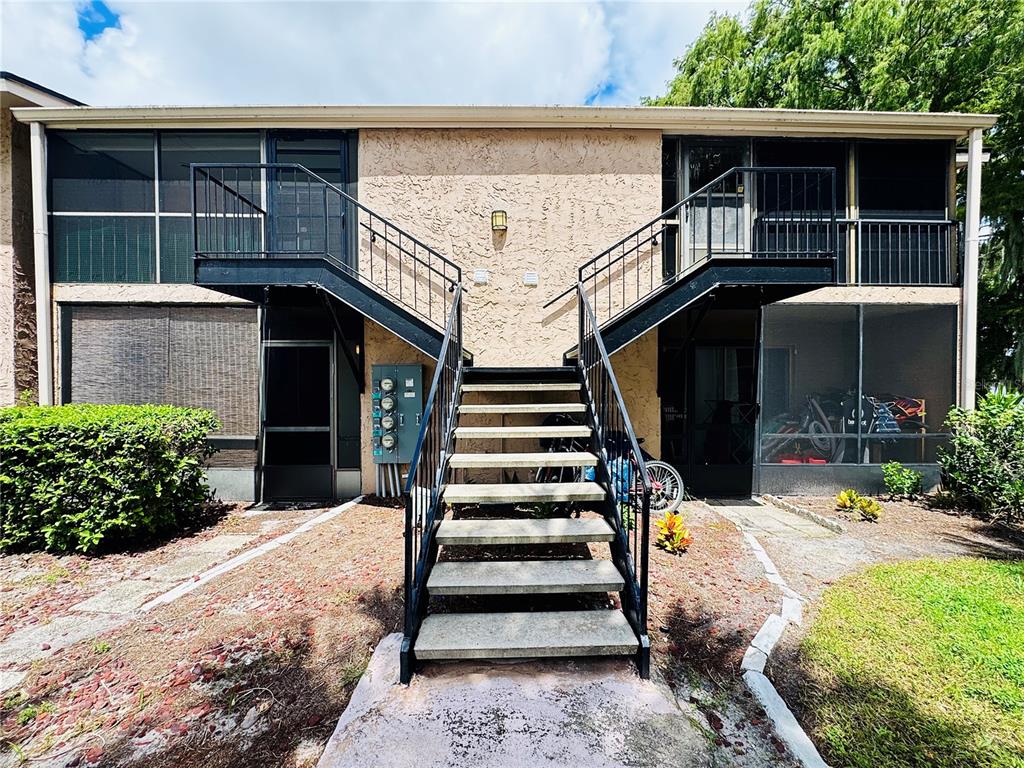 An exterior view of a two-story apartment building with a central staircase and screened balconies — 1180 PASEO DEL MAR UNIT C, CASSELBERRY, FL