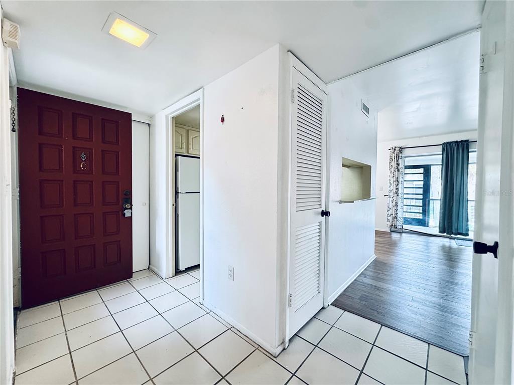 An entryway with white tile floors leads to a kitchen and a living area — 1180 PASEO DEL MAR UNIT C, CASSELBERRY, FL