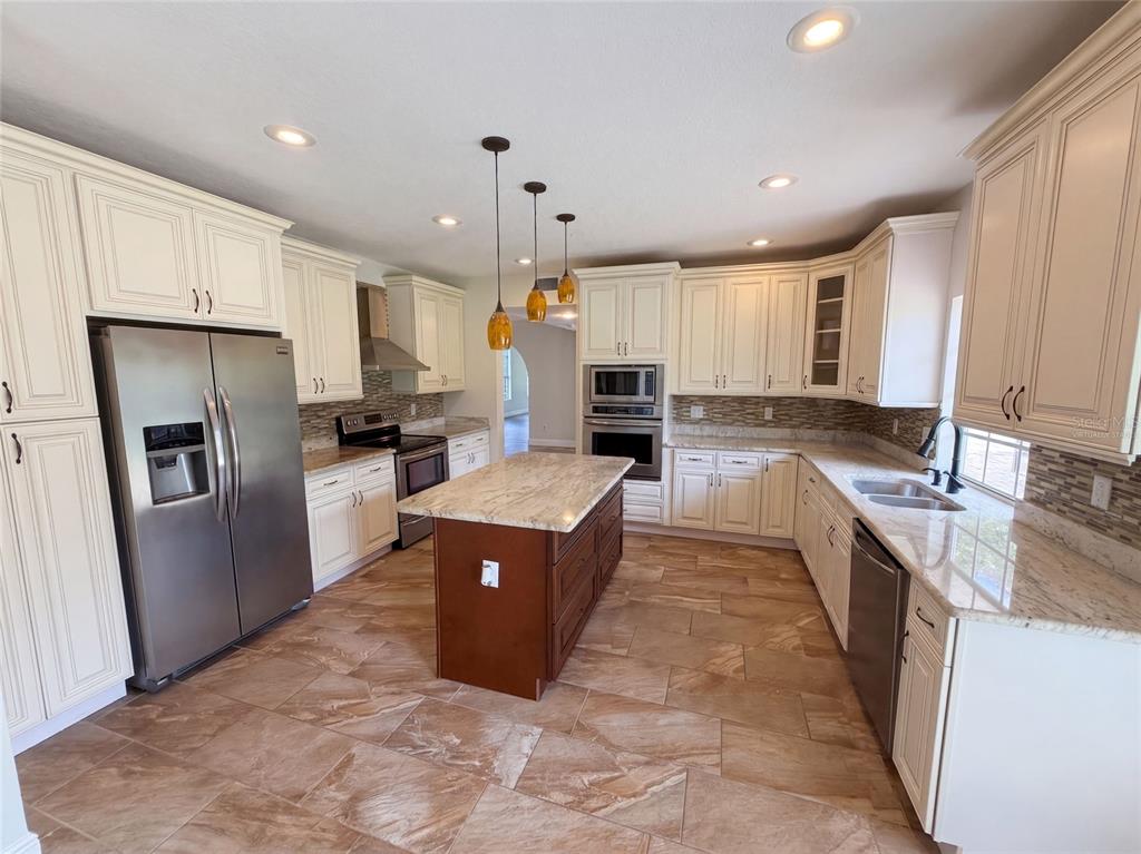 A kitchen features cream-colored cabinets, a dark wood island, stainless steel appliances, and tile flooring — 120 LONGBRANCH ROAD, WINTER PARK, FL