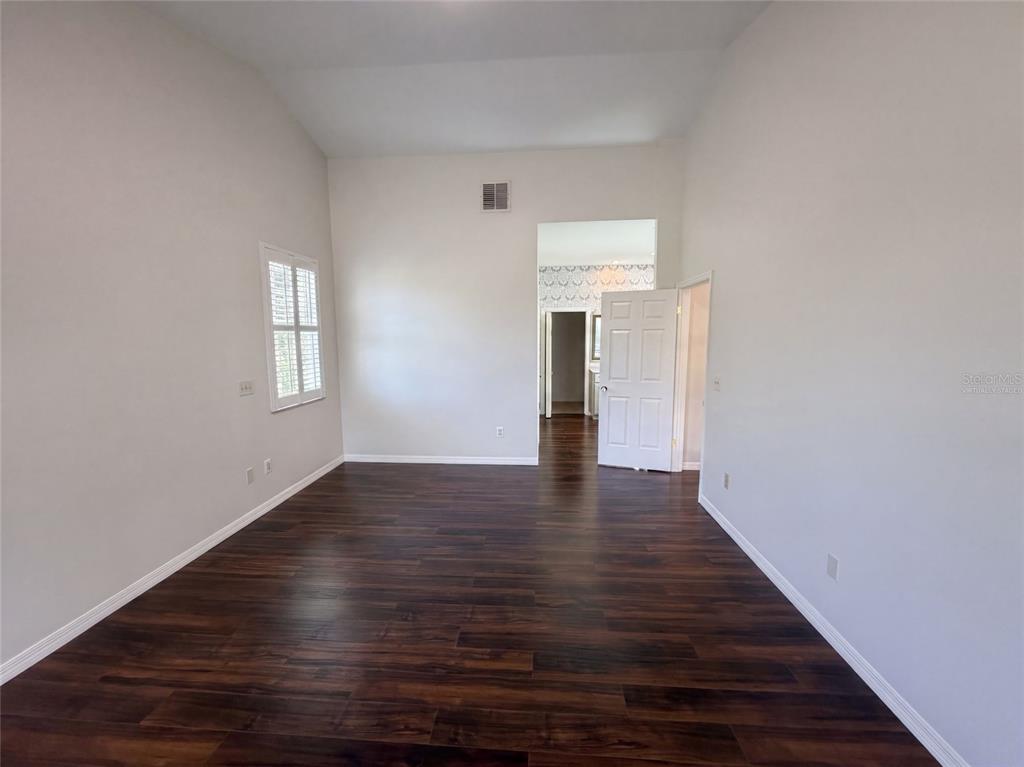 An empty room with dark wood flooring, white walls, and a doorway leading to another room — 120 LONGBRANCH ROAD, WINTER PARK, FL