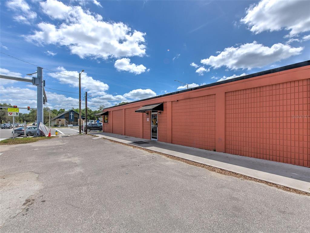 An exterior view of a single-story commercial building with orange tiled walls and a sidewalk — 8001 S 301 HIGHWAY, RIVERVIEW, FL