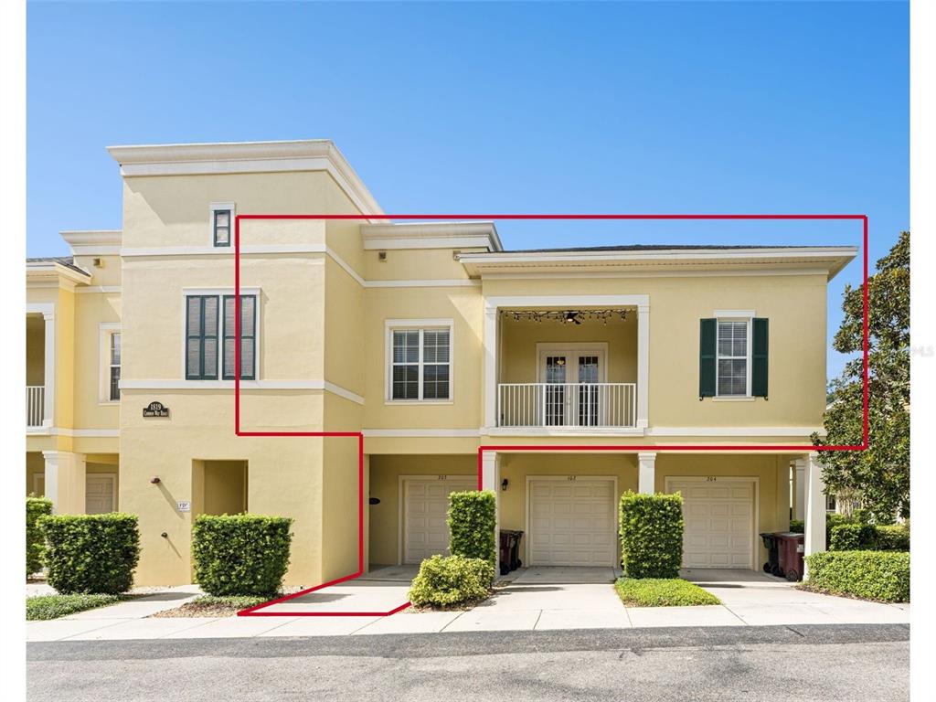 A two-story yellow stucco townhouse with a balcony, three garage doors, and green shutters — 1819 COMMON WAY ROAD UNIT 203, ORLANDO, FL