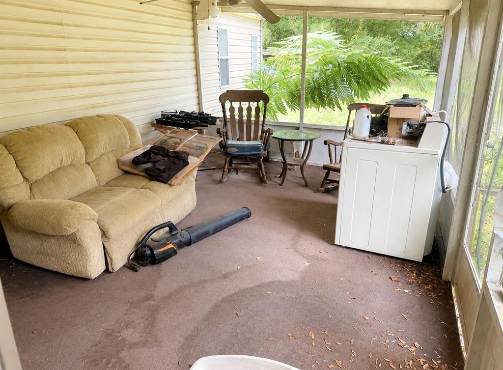 A screened-in porch features a tan loveseat, a rocking chair, and a white washing machine — 15171 NE 154TH LANE, FORT MC COY, FL