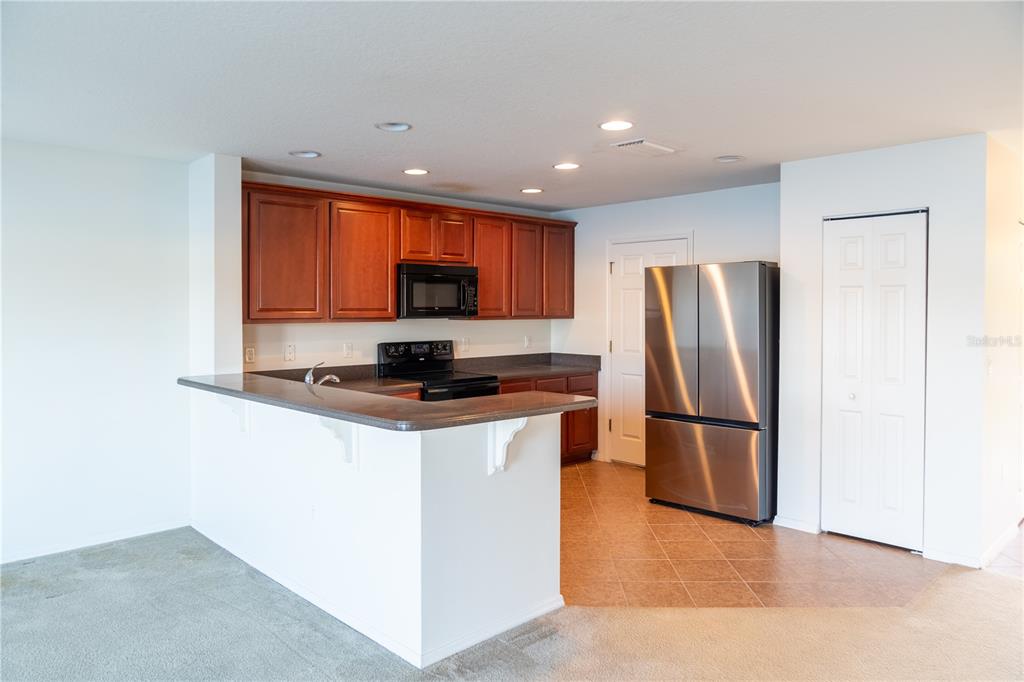 A kitchen features wood cabinets, dark countertops, stainless steel appliances, and a breakfast bar — 3733 EAGLE PRESERVE POINT, SANFORD, FL