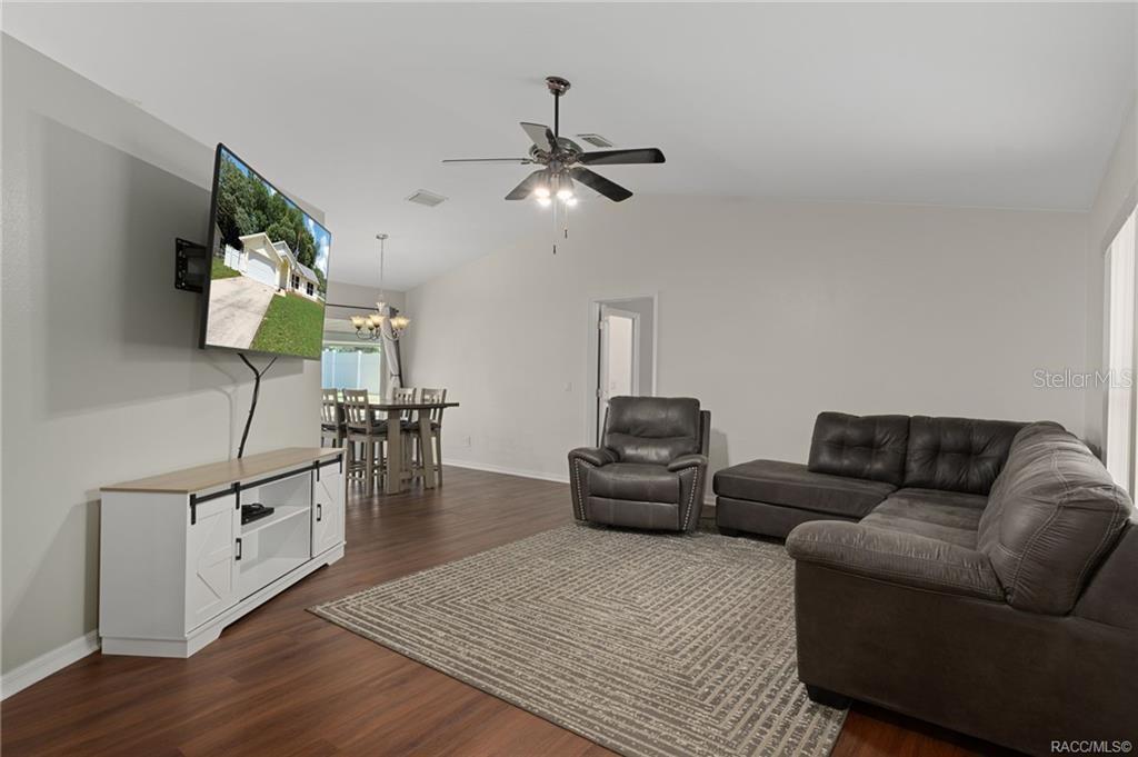 A living room features a sectional sofa, a television on a stand, and wood flooring — 1014 STETSON TERRACE, INVERNESS, FL