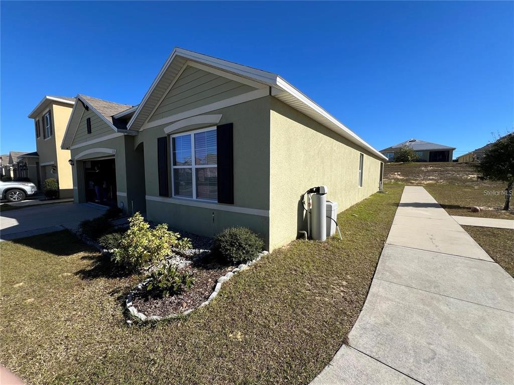The exterior of a light green house features a garage, a sidewalk, and landscaping — 120 PANDA WAY, DAVENPORT, FL
