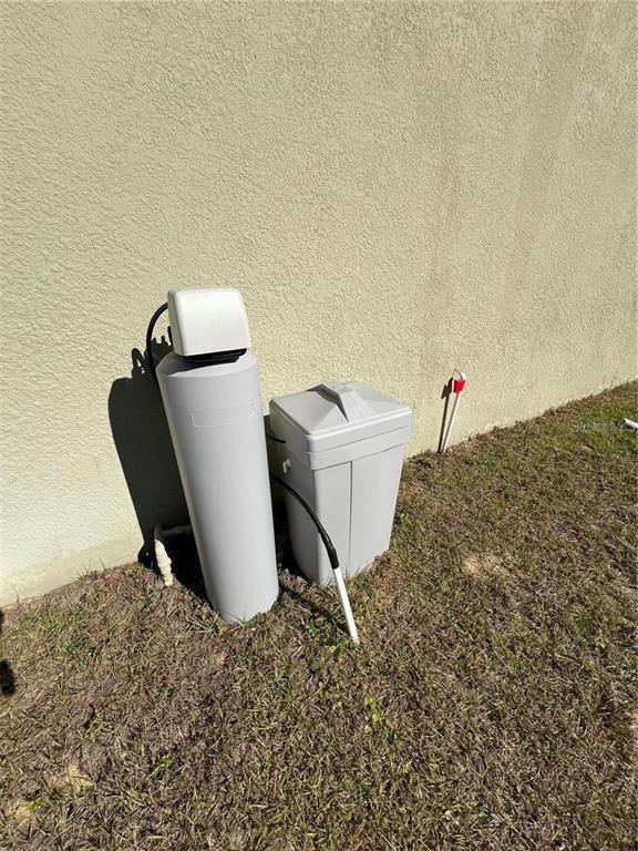 A water softener system sits on the grass against the exterior wall of a house — 120 PANDA WAY, DAVENPORT, FL