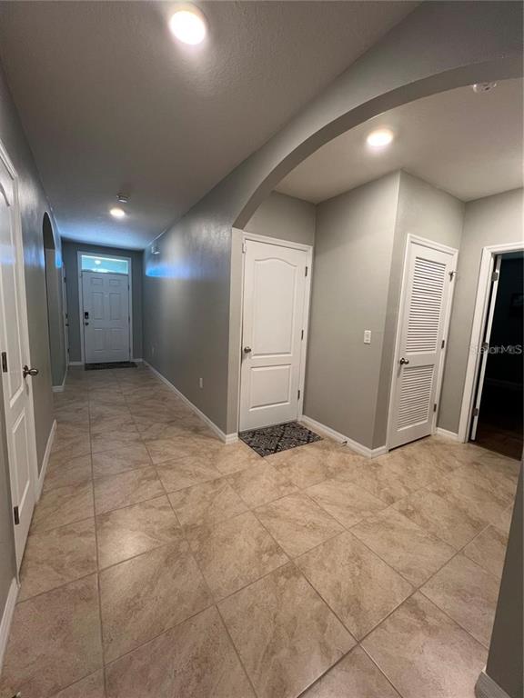 A tiled hallway features a white front door, two interior doors, and recessed ceiling lighting — 120 PANDA WAY, DAVENPORT, FL