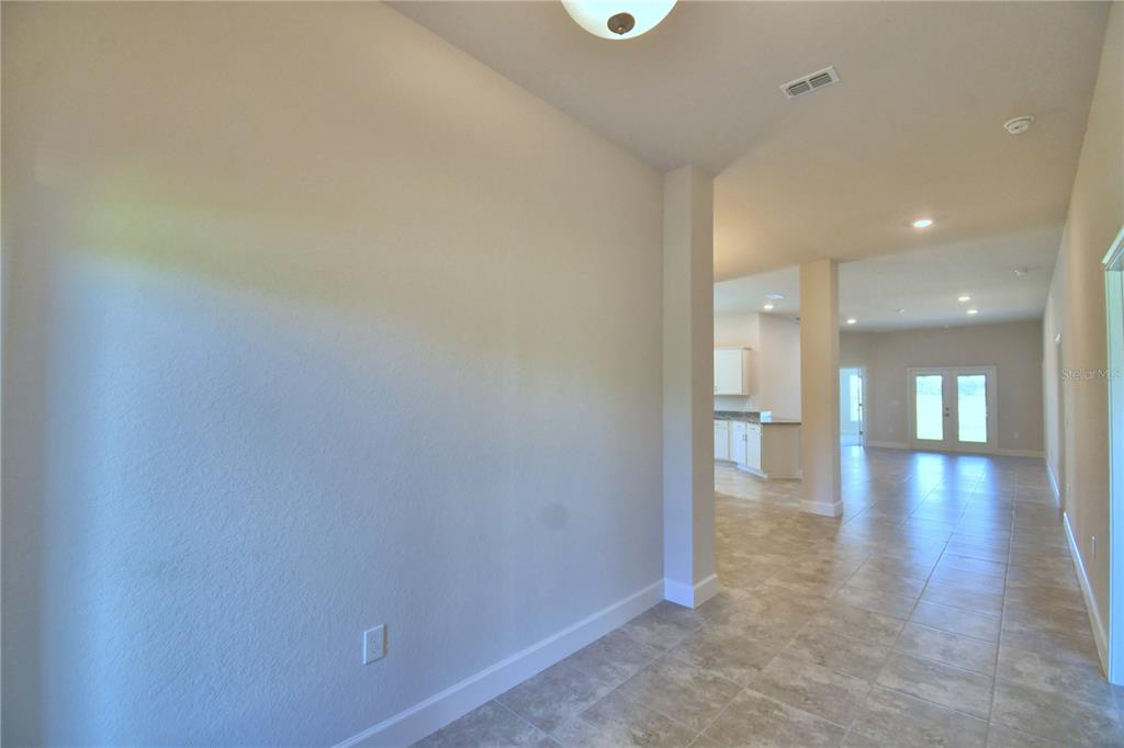 An interior view shows a tiled entryway leading into an open-concept living area and kitchen — 4616 CALAMINT LANE, AUBURNDALE, FL