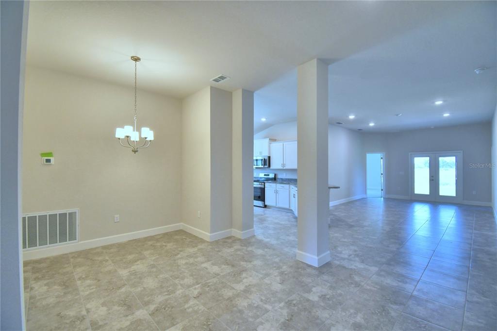 An open-concept dining area features tile flooring, a chandelier, and a view into the kitchen — 4616 CALAMINT LANE, AUBURNDALE, FL