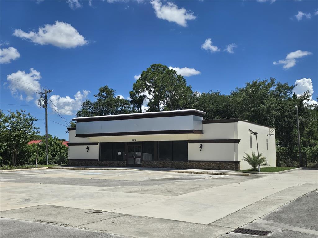 A single-story commercial building with a large parking lot under a bright blue sky — 8801 20TH STREET, VERO BEACH, FL