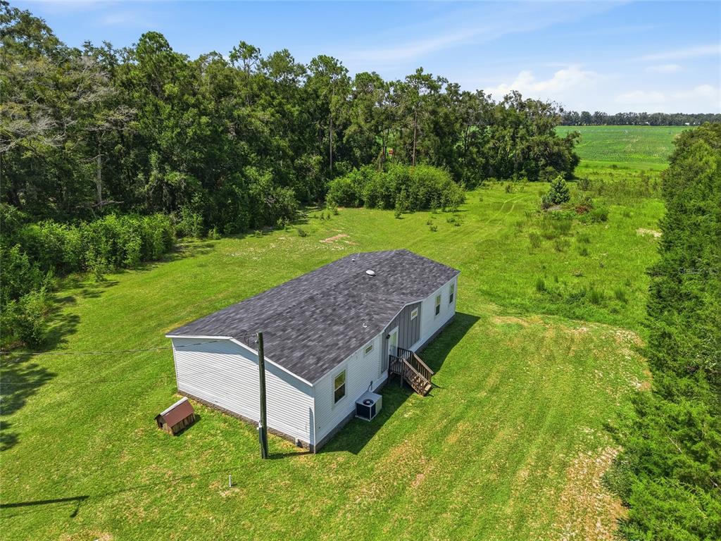 An aerial view shows a white manufactured home situated on a large, grassy rural lot — 4754 SW 10TH STREET, BELL, FL