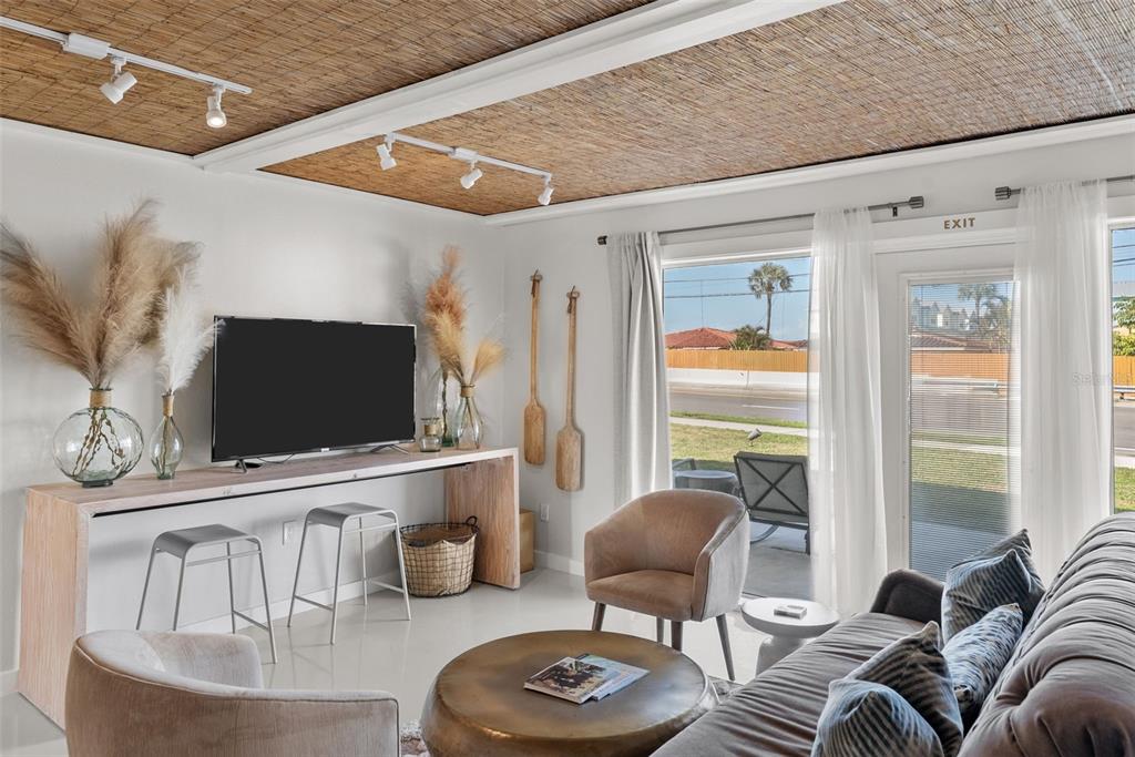 A living room features a textured ceiling, a television on a console, and patio access — 439 CAUSEWAY BOULEVARD, DUNEDIN, FL