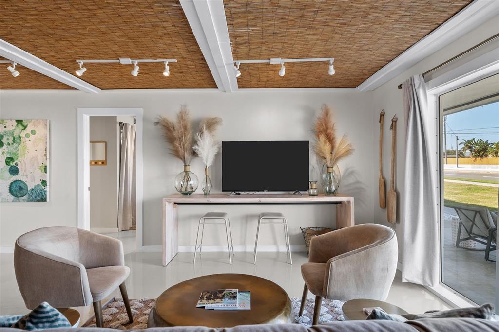 A living room features a TV console, two armchairs, and a textured bamboo ceiling — 439 CAUSEWAY BOULEVARD, DUNEDIN, FL