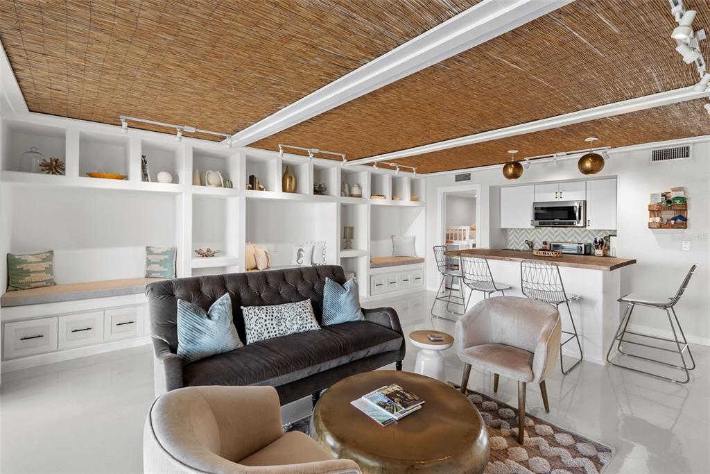 A living room features built-in shelving, a dark sofa, and a textured bamboo ceiling — 439 CAUSEWAY BOULEVARD, DUNEDIN, FL