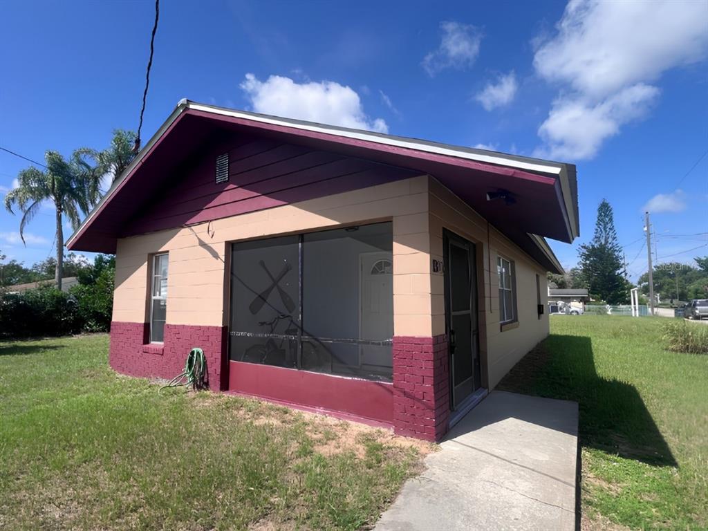 A single-story house with a screened-in porch, tan and maroon exterior, and a concrete walkway — 1300 S CAROLINA AVENUE, AVON PARK, FL