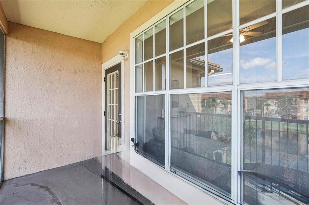 A screened-in balcony overlooks a pond and apartment buildings under a clear blue sky — 5536 METROWEST BOULEVARD UNIT 8-311, ORLANDO, FL