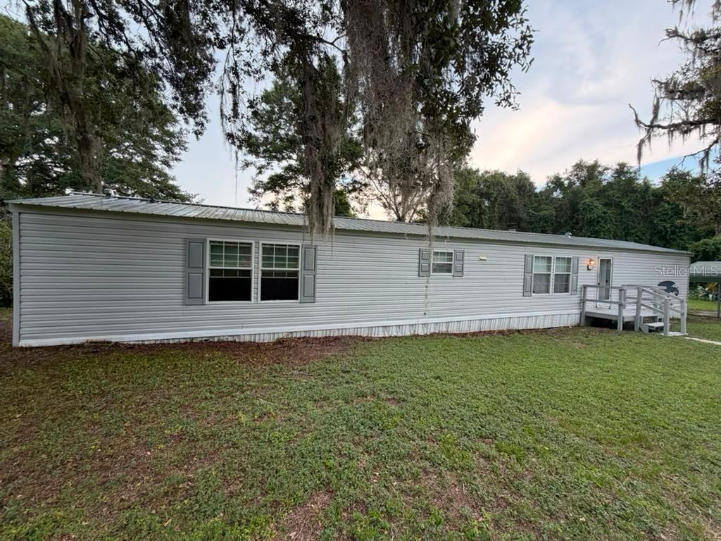 A single-story manufactured home with light gray siding and a metal roof sits on grass — 17689 SE 14TH STREET, SILVER SPRINGS, FL