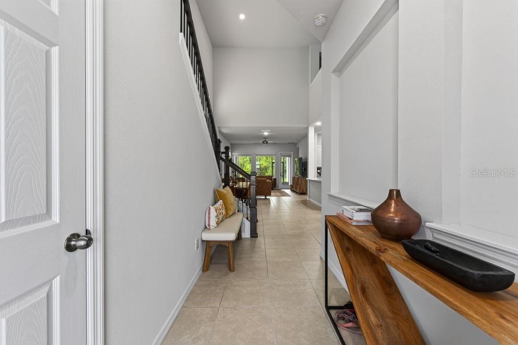 A bright entryway features a staircase with a wooden railing and a console table — 28583 COZY CREEK DRIVE, WESLEY CHAPEL, FL