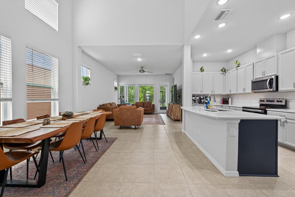 An open-concept kitchen and dining area features white cabinetry, a large island, and tile flooring — 28583 COZY CREEK DRIVE, WESLEY CHAPEL, FL