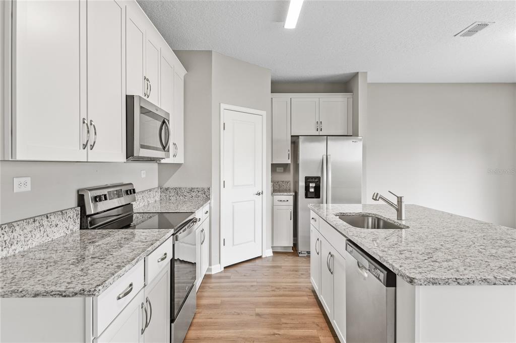A kitchen with white cabinets, granite countertops, stainless steel appliances, and a central island — 2754 LAUREL FALLS DRIVE, GREEN COVE SPRINGS, FL