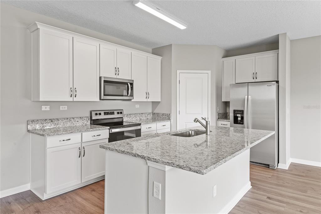 A kitchen with white cabinets, granite countertops, stainless steel appliances, and a central island — 2754 LAUREL FALLS DRIVE, GREEN COVE SPRINGS, FL