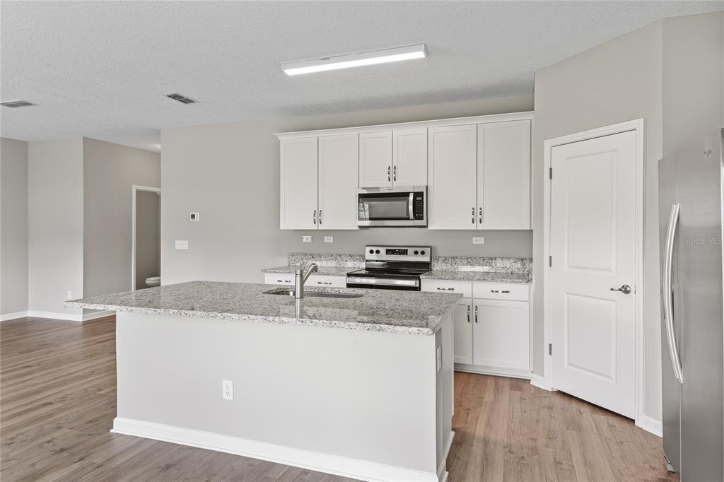 A kitchen with white cabinets, granite countertops, a center island, and stainless steel appliances — 2754 LAUREL FALLS DRIVE, GREEN COVE SPRINGS, FL