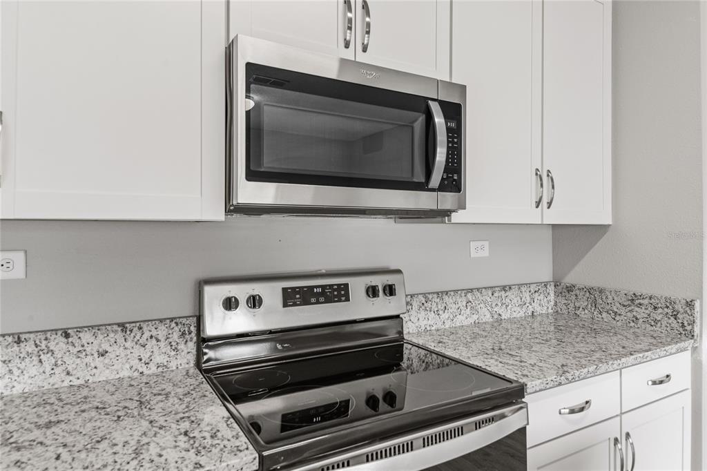 A kitchen features white cabinets, granite countertops, and stainless steel appliances — 2754 LAUREL FALLS DRIVE, GREEN COVE SPRINGS, FL