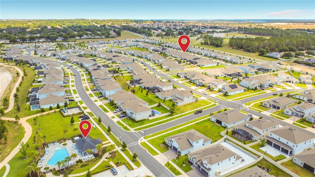 An aerial view shows a suburban neighborhood with houses, a community pool, and paved streets — 4485 DAVOS DRIVE, CLERMONT, FL