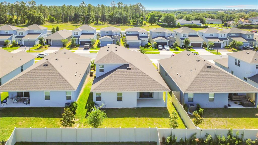 An aerial view shows the backyards and rear exteriors of several suburban houses with fenced lawns — 4485 DAVOS DRIVE, CLERMONT, FL